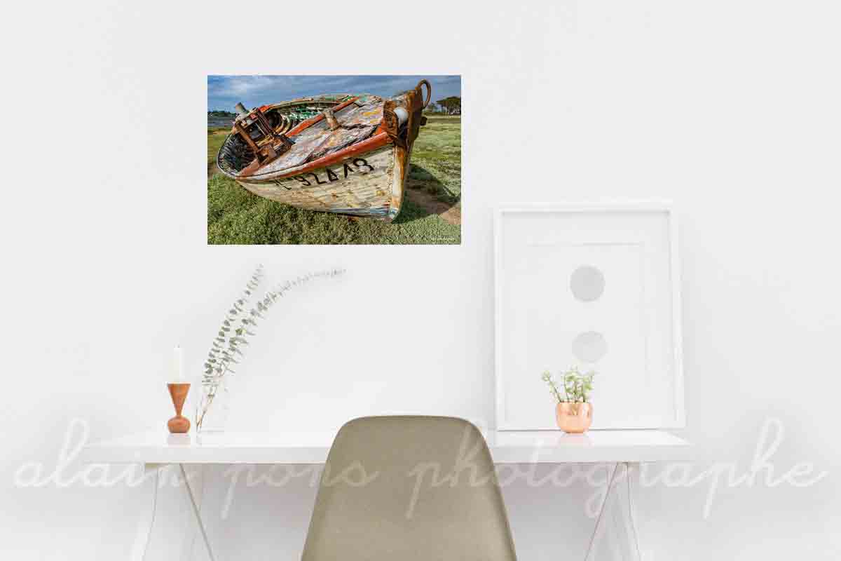 Photographie d'une épave d'un petit bateau de pèche à Trébeurden, en couleur, présentée ici en décoration dans un bureau.