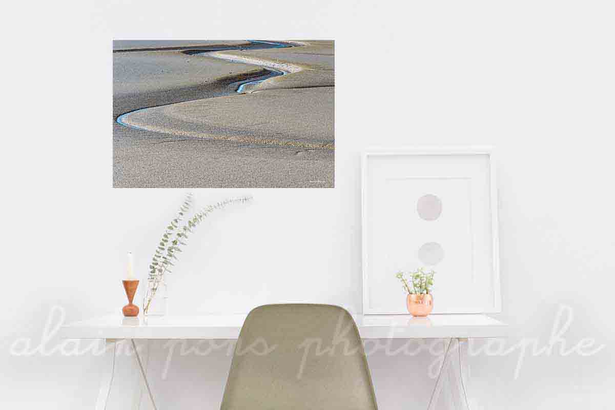 Un serpent de mer en Baie de Somme, ondulation d'un cours d'eau sur une étendue de sable, photographie présentée en décoration dans un bureau.