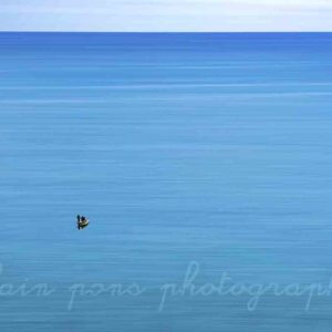 photographie de deux pêcheurs dans une barque sur une mer bleue. alain pons photographe®