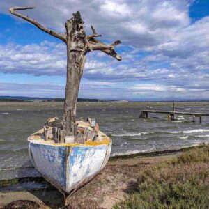 Photographie d'un bateau, un canot avec un mât en tronc d'arbre au bord d'un étang dans les Corbières, version couleur.