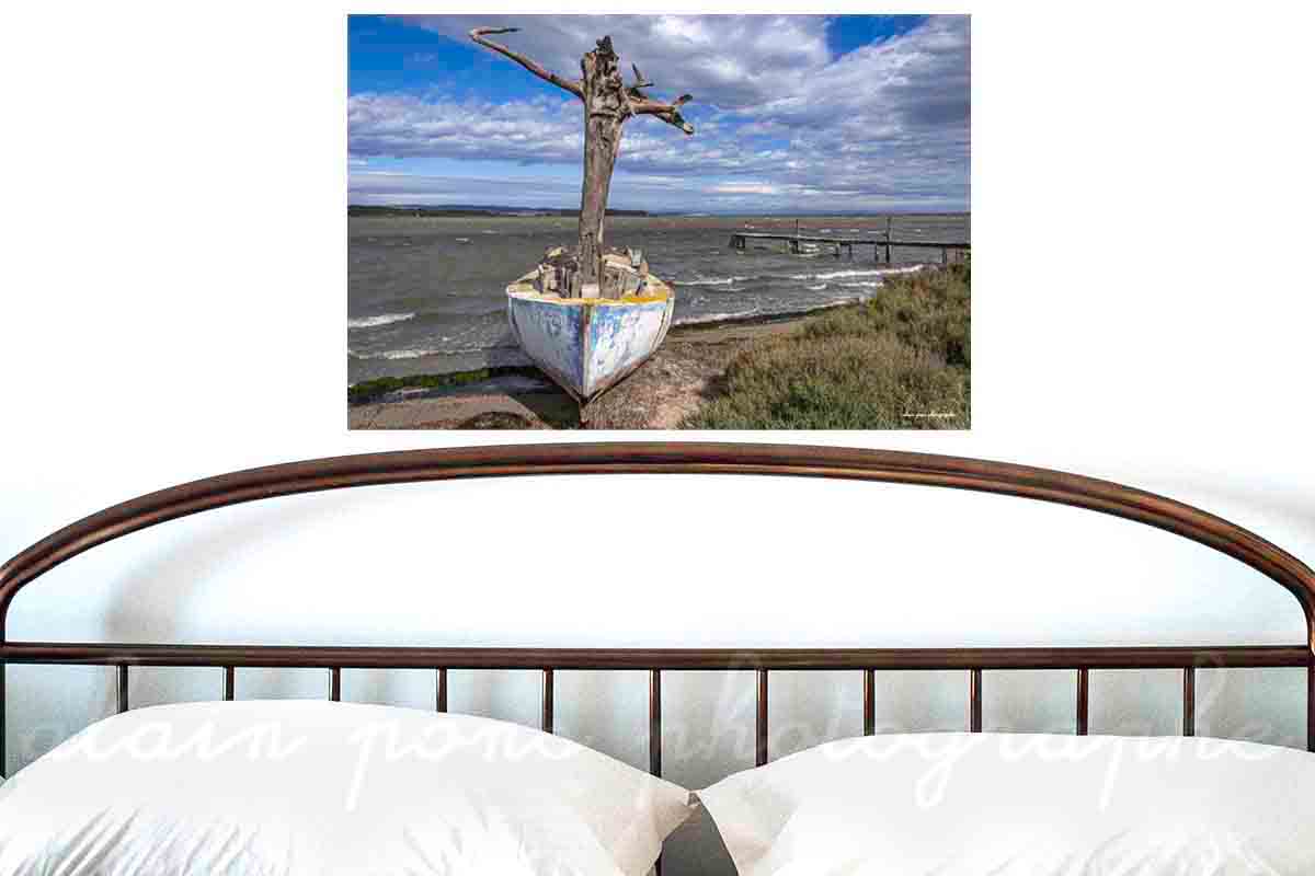 Photographie d'un bateau, un canot avec un mât en tronc d'arbre au bord d'un étang dans les Corbières. Ici présenté en simulation de décoration dans une chambre. Version couleur.