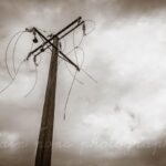photographie d'un pylône électrique, fils au vent
