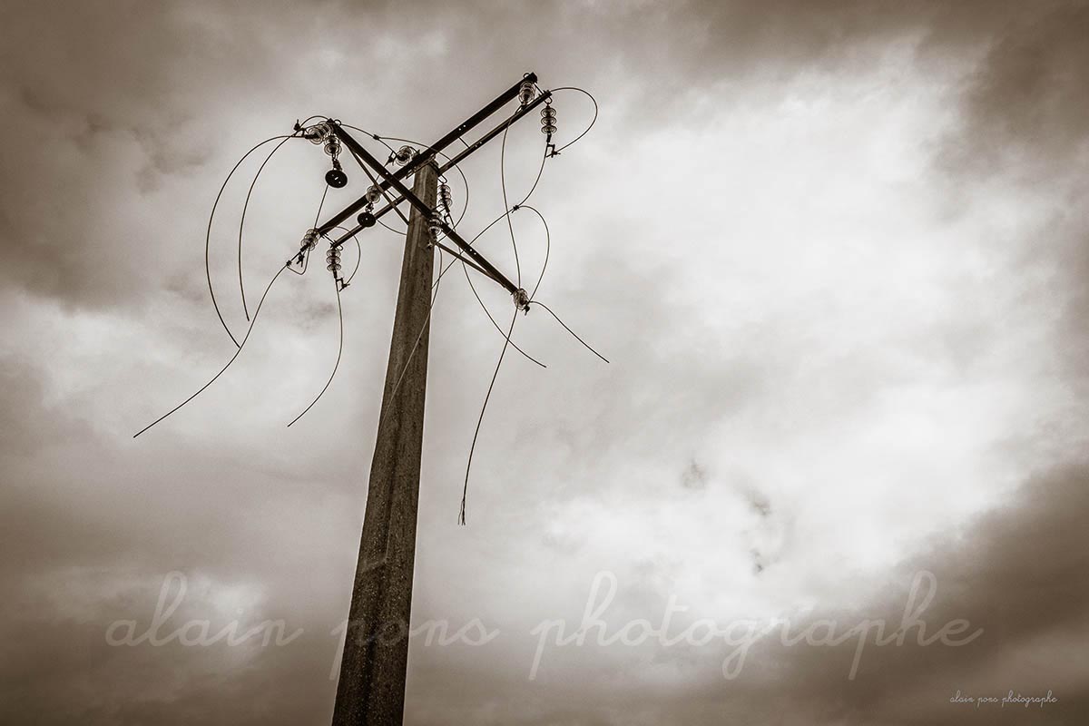 photographie d'un pylône électrique, avec les fils au vent, fils coupés et pendants, par alain pons photographe®