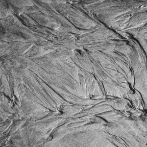 photographie de sable noir en Bretagne, figures libres, en noir et blanc. Présentation dans un bureau.