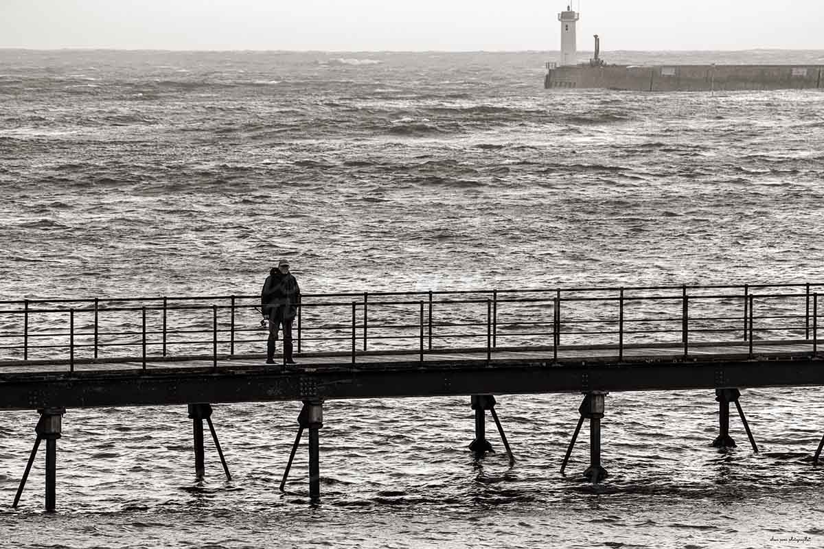 photographie de la passerelle des capucins, un pêcheur, le phare du Raoulic, à Audierne