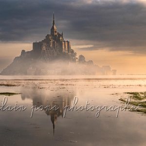 Photographie du Mont-Saint-Michel au lever du soleil pendant une grande marée en octobre 2025
