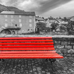photographie le banc rouge à Meyrueis. Une photographie désaturée pour avoir le banc rouge prédominant dans le paysage de ce village de Lozère.