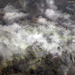 photographie du village de Chèze dans les nuages, département des Hautes-Pyrénées. En couleur, format horizontal.