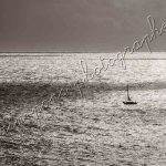 photographie le petit voilier dans l'immensité de la mer
