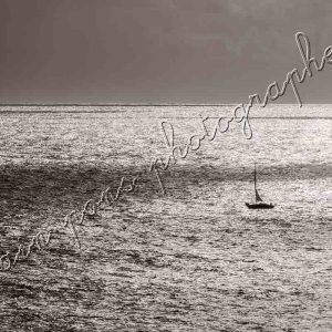 photographie le petit voilier dans l'immensité de la mer